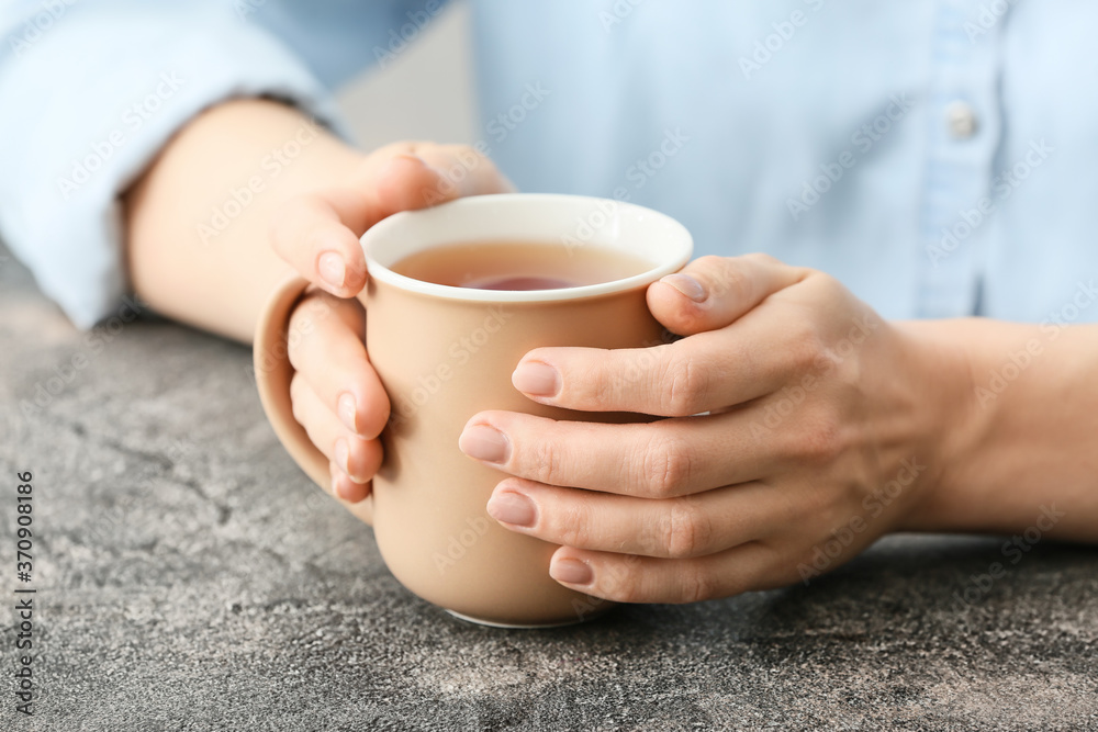 Woman with cup of hot tea at table, closeup
