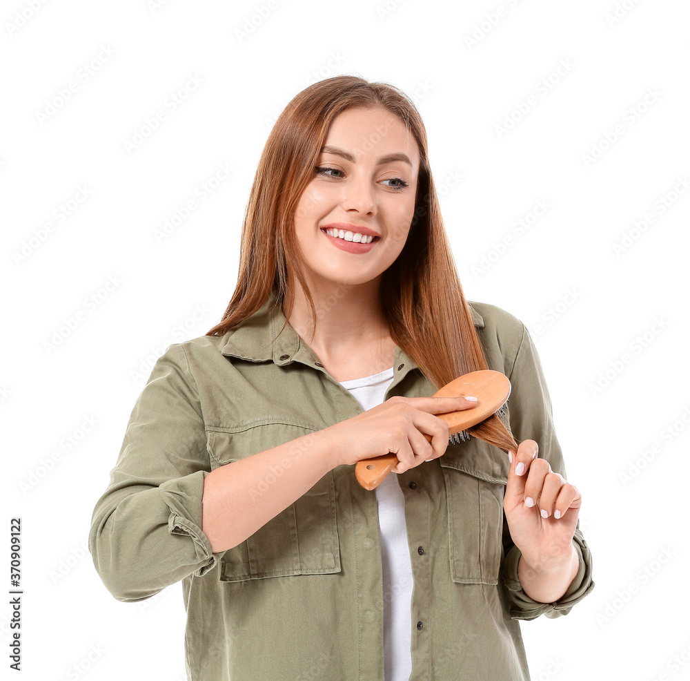 Young woman brushing hair on white background