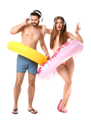 Poster - Young couple with headphones and inflatable rings on white background