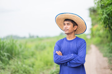 Asian farmer man standing and cross hands looking sky at green farm