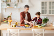 © deniskomarov - Father and son cooking dinner standing on kitchen