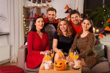 Wall Mural - friendship, holiday and people concept - group of happy smiling friends in halloween costumes of vampire, devil, witch and cheetah at home party at night