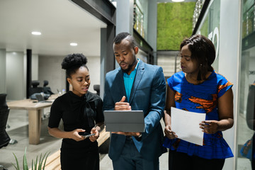 Three North African businesspeople walking in an office using a tablet