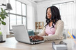 © Syda Productions - remote job, technology and people concept - african american young woman with laptop computer working at home office