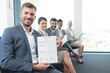 © focusandblur - Happy businessman showing his resume while candidates are waiting in line for job interview