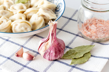 Wall Mural - Head of garlic and bay leaf on the background of a plate with dumplings