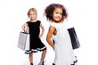 © ribalka yuli - Little fashionable girls girlfriends of two different nationalities posing on a white background with shopping bags.