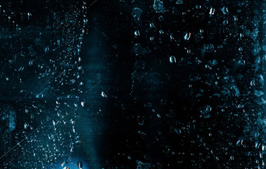 Wet glass background. Stained texture. Teal blue distressed window with water drops.