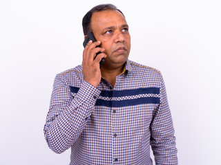 Portrait of mature overweight Indian businessman talking on the phone