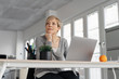 © contrastwerkstatt - Pensive woman sitting in front of laptop at office