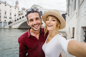 Wall Mural - Young couple taking a selfie portrait in front of Rialto Bridge in Venice, Italy.