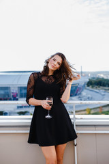 Wall Mural - woman with a glass of wine on the balcony against the background of the city