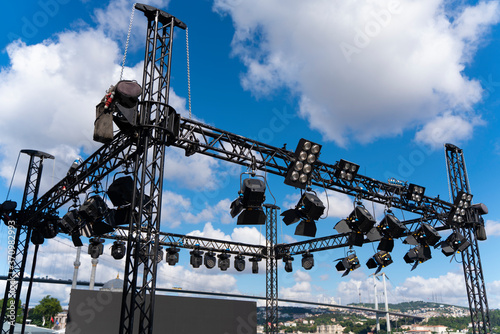 Installation of professional sound, light, led panel, video and stage equipment for a concert. Stage lighting equipment is clamped on a truss for lifting. Flight cases with cables..