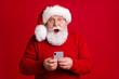 Photo of amazed retired pensioner man in santa claus headwear use smartphone impressed jolly holly x-mas fairy discounts wear sweater jumper isolated over bright shine color background