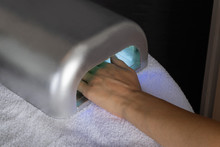 Woman Hand In UV Lamp Drying New Nails Polish In A Salon. Beauty And Manicure Concept. Copy Space For Design, Close Up, Selective Focus