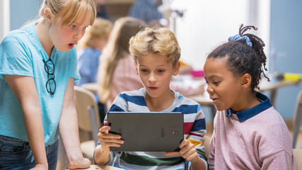 Poster - Elementary School Computer Science Class: Two Girls and Boy Use Digital Tablet Computer with Augmented Reality Software, They’re Excited, Full of Wonder, Curiosity. Children in STEM, Playing, Learning