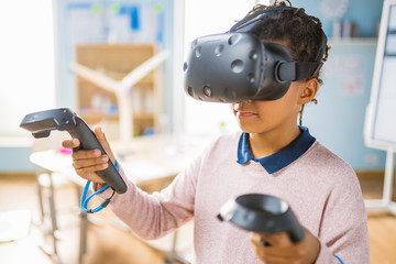 Fototapete - Elementary School Computer Science Class: Cute Girl Wearing Augmented Reality Headset and Using Controllers Learns Lessons in Virtual Reality Excited, Curious and Interested in Knowledge