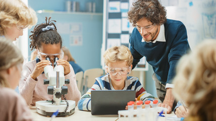 Poster - Elementary School Science Classroom: Cute Little Girl Looks Under Microscope, Boy Uses Digital Tablet Computer to Check Information on the Internet. Teacher Observes from Behind