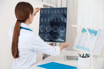 Poster - Orthopedist examining X-ray picture at desk in clinic