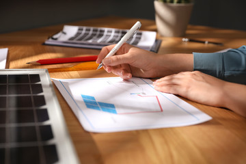 Woman working on house project with solar panels at table in office, closeup