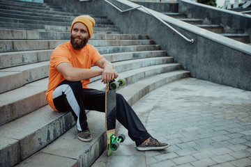 Poster - Handsome young stylish hipster guy with beard with a skateboard