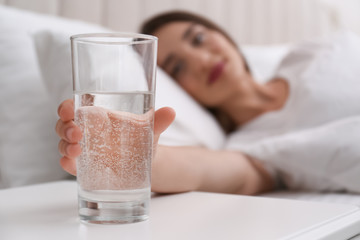 Canvas Print - Young woman taking glass of water from nightstand at home, closeup