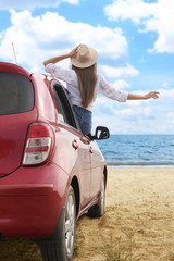 Wall Mural - Happy woman leaning out of car window on beach. Summer vacation trip