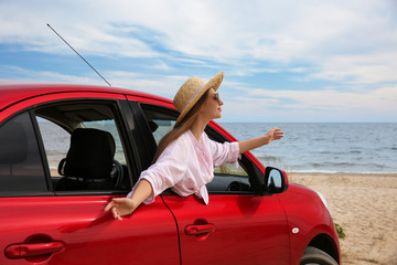 Wall Mural - Happy woman leaning out of car window on beach. Summer vacation trip