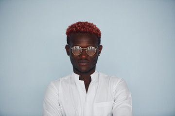 Young african american man in white formal clothes standing against wall indoors