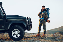 Portrait Of A Young Traveler Man In Hiking Equipment Standing Near His Off-road Car