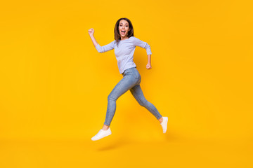 Poster - Full length body size profile side view of attractive sporty cheerful cheery girl jumping running sprint fast action activity life lifestyle isolated bright vivid shine vibrant yellow color background