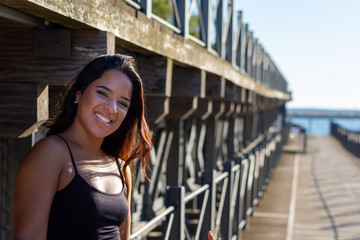 young woman sitting or standing next to a wooden and iron bridge