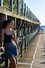 young woman sitting or standing next to a wooden and iron bridge