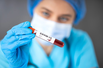 Nurse wearing respirator mask holding a positive blood test result for the COVID-19