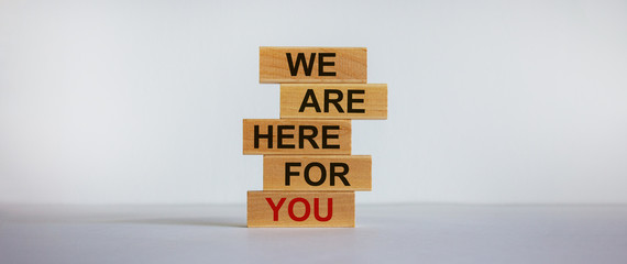 Wooden blocks with text 'we are here for you'. Beautiful white background, copy space. Business concept.