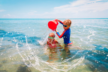 Wall Mural - happy boy and girl play on beach, kids splash water and have fun