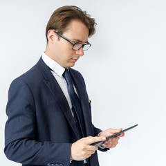 Portrait of a businessman in a blue suit holding an electronic tablet in his hands. White background.