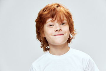 Wall Mural - Red-haired boy with freckles on his face close-up white t-shirt cropped 