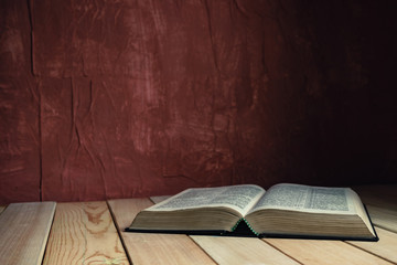 Aufkleber - Open Holy Bible on a old wooden table. Beautiful red wall background..
