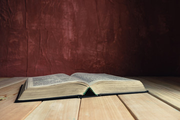 Wall Mural - Open Holy Bible on a old wooden table. Beautiful red wall background..