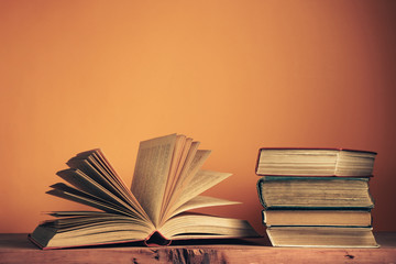 Poster - Old books on a old wooden table. Beautiful orange wall background.