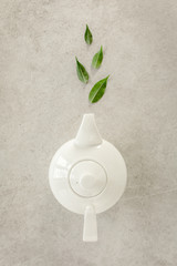 Wall Mural - Herbal tea in a white teapot, with green tea leaves. Flat lay, top view. Tea concept