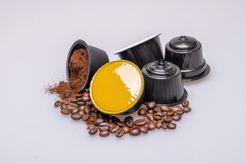 Wall Mural - Open coffee capsule with grounded coffee inside, assorted coffee pods and roasted coffee beans on white background