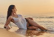 Sexy woman posing on beach near the sea at sunrise