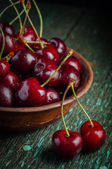 Wall Mural - Clay plate with ripe red cherries on a wooden old table.