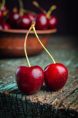 Wall Mural - Clay plate with ripe red cherries on a wooden old table.