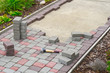 worker laying paving stones. stone pavement, construction worker laying cobblestone rocks on sand.