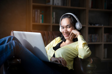 Wall Mural - Businesswoman working online at the home office via laptop. Asian young entrepreneur watching webinars and talking during meeting video conferences call with team. Woman sitting at sofa in living room