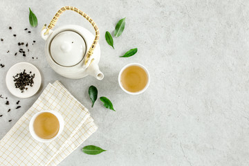 Wall Mural - Herbal tea with two white tea cups and teapot, with green tea leaves. Flat lay, top view. Tea concept