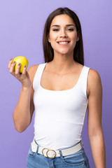 Poster - Young caucasian woman isolated on purple background with an apple